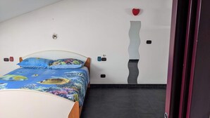 Un dormitorio con una cama, una pared con una grieta grande y una decoración con forma de corazón rojo.