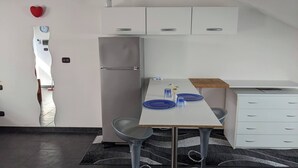 Una cocina compacta con refrigerador, una mesa blanca con platos azules y una pequeña encimera.
