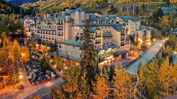 A large, multi-story hotel with a central courtyard, surrounded by trees and hills. - Contemporary 3 Bedroom Ski In, Ski Out Condo in the Heart of Beaver Creek Village (Avon)