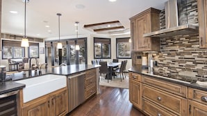A spacious kitchen with wooden cabinets, a large island, and a dining area with a table and chairs. - Contemporary 3 Bedroom Ski In, Ski Out Condo in the Heart of Beaver Creek Village (Avon)