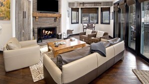 A modern living room with a fireplace, leather sofas, a coffee table, and large windows. - Contemporary 3 Bedroom Ski In, Ski Out Condo in the Heart of Beaver Creek Village (Avon)