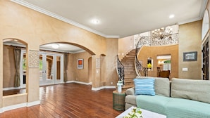 Ein geräumiger Wohnbereich mit Holzboden, einer Treppe und einem hellgrünen Sofa.