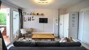 A modern living room with a sofa, a wooden table, and a TV mounted on the wall. - Serene Lakeview Retreat (San Martín de Valdeiglesias)