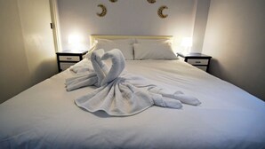 A neatly made bed with a towel arranged in a heart shape, two bedside tables with lamps, and wall art of crescent moons. - Serene Lakeview Retreat (San Martín de Valdeiglesias)