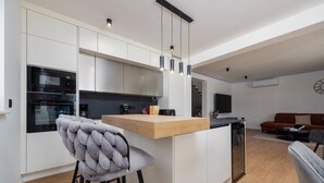 A modern kitchen with white cabinets, a wooden countertop, and a built-in oven. - Villa Roma Murvica Zadarvillas (Policnik)