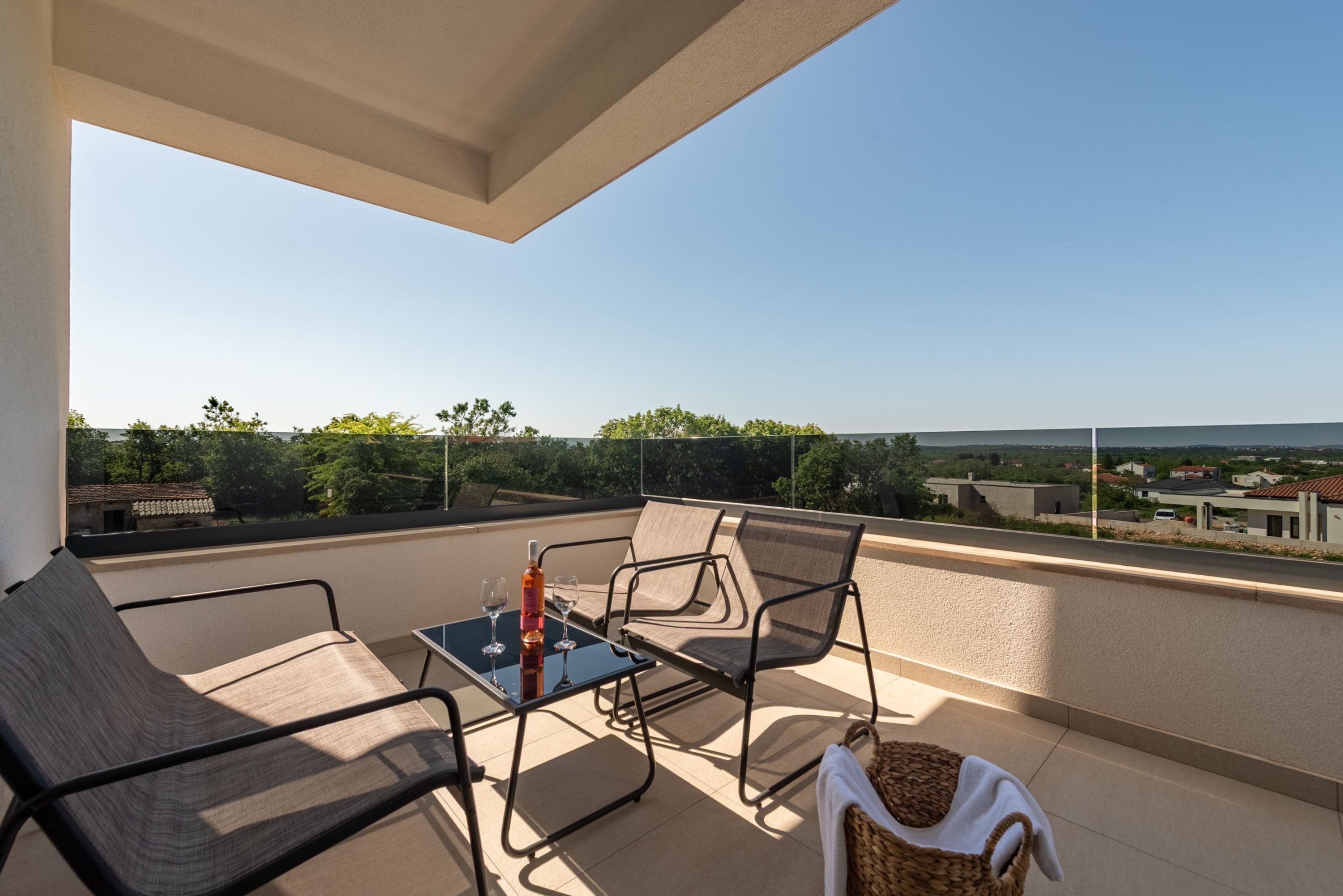 A balcony with a table, two chairs, and a bottle of wine.