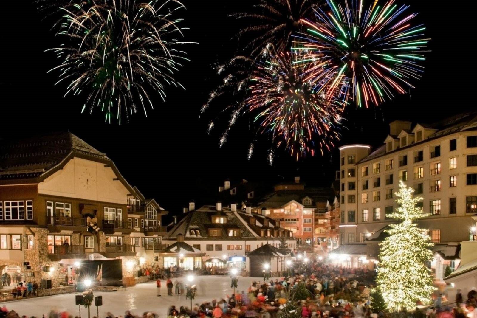 A town square with a crowd, buildings, and a Christmas tree.