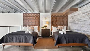 A hotel room with two beds, a wooden headboard, a nightstand, and a decorative wall panel.