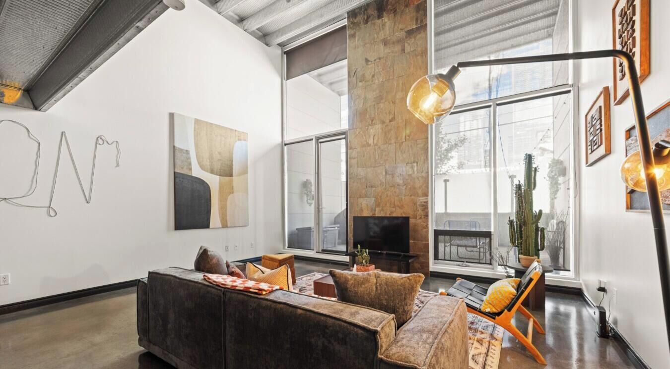 Un salon moderne avec un mur d’accent en pierre, une grande fenêtre et un coin salon confortable.