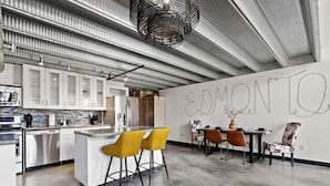 A modern kitchen with a bar area, a dining table with chairs, and a wall with the word "EDMONTQ" written on it.
