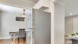 Eine moderne Küche mit einem Edelstahlkühlschrank, einem Esstisch mit Stühlen und einer Pendelleuchte.