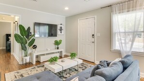 Ein modernes Wohnzimmer mit einem grauen Sofa, einem weißen Couchtisch und einer großen Pflanze.