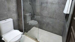 Een moderne badkamer met een douchecabine van glas, een wit toilet en een handdoekhouder.
