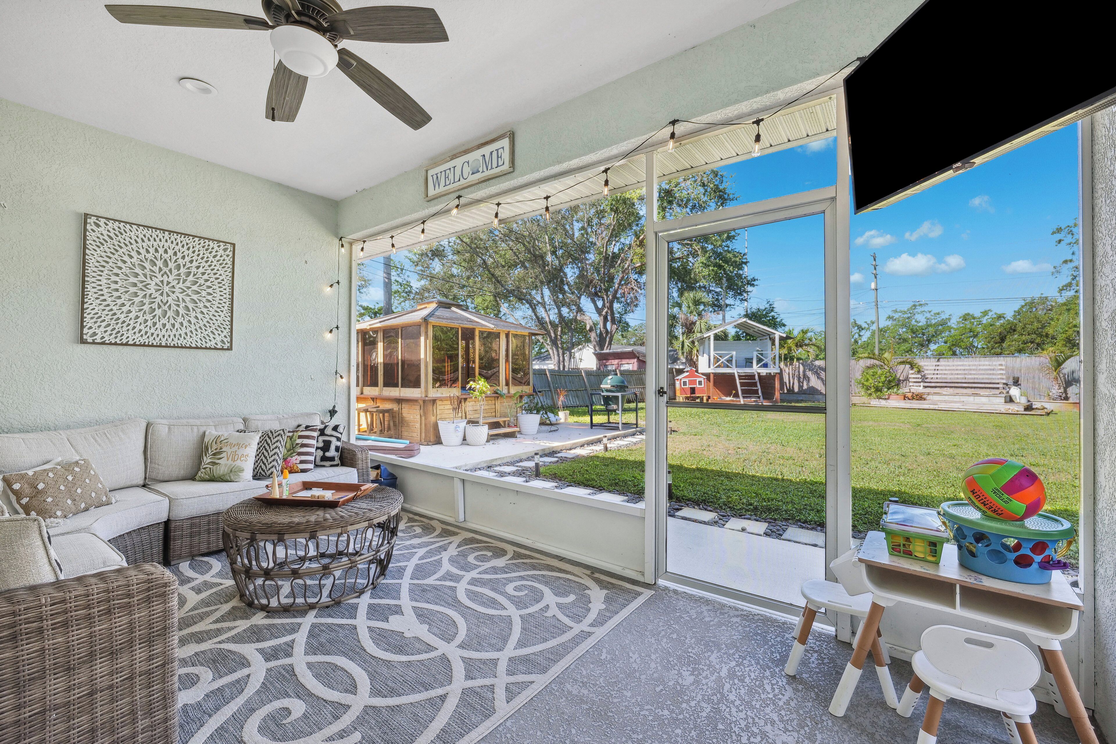 A spacious patio with a wicker sofa, a round coffee table, and a children's play area with toys and a ball.