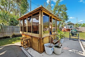 Ein hölzerner Pavillon mit Glasverkleidung, einer Holzbank und Topfpflanzen.