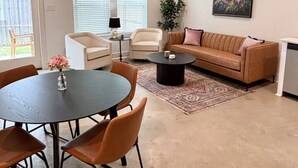 Una sala de estar moderna con una mesa redonda de comedor, dos sillones, un sofá, una mesita de centro y un ventilador de techo.