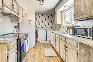Una cucina con mobili in legno, un forno a microonde, un fornello e un frigorifero.