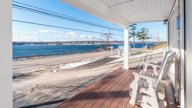 A wooden deck with a view of a coastal road and a body of water.