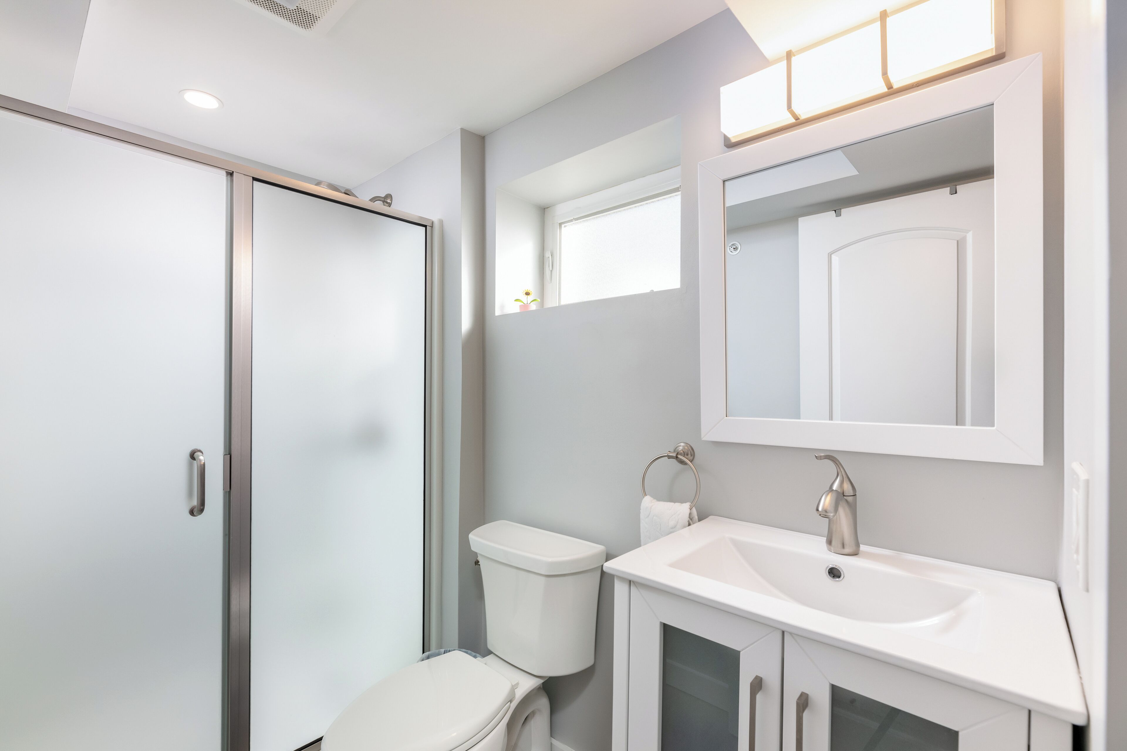 Et moderne badeværelse med toilet, håndvask og spejl.
