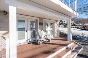 A covered porch with a white bench, a welcome sign, and a view of a snowy landscape. - Steps to Beach: Lake-view Laconia Getaway! (Laconia)