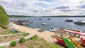 A lakeside dock with boats, a sandy beach, and a lifeguard station.