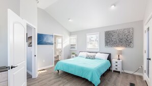 A bedroom with a bed, bedside table, wall art, and a door.