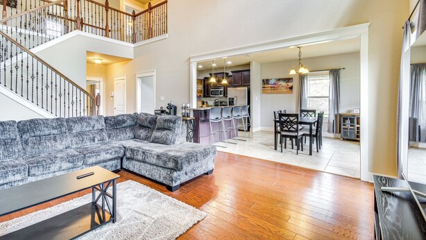 A spacious living room with a large sectional sofa, a wooden staircase, and a kitchen area visible through an open doorway. - 10 Mi to Gulfport Beaches: Family Home w/ Patio (Gulfport)