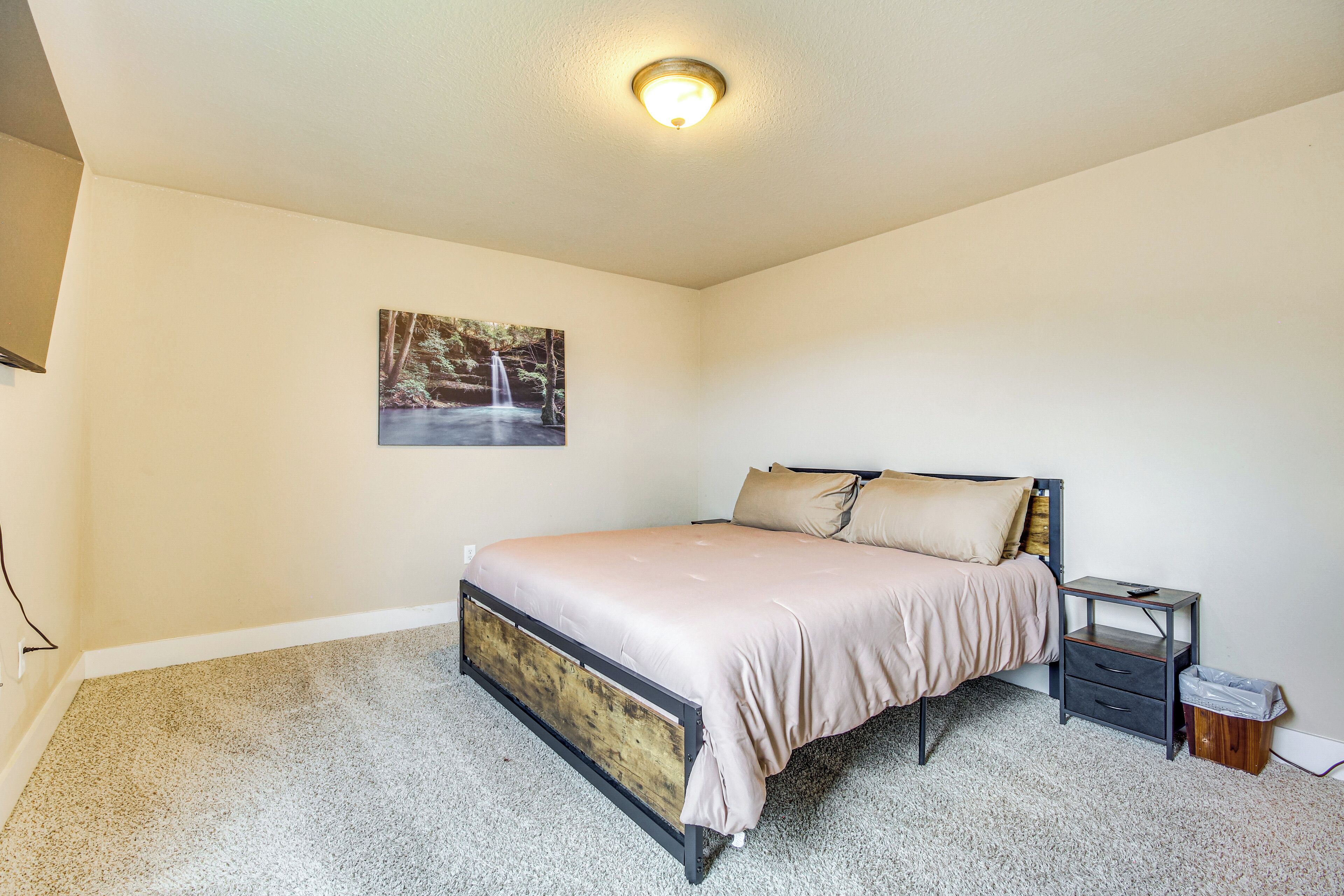 A bedroom with a bed, a nightstand, a trash bin, and a ceiling light fixture.
