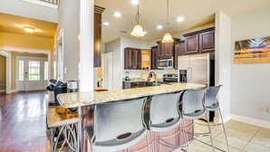 A spacious kitchen with a central island, bar stools, and modern appliances. - 10 Mi to Gulfport Beaches: Family Home w/ Patio (Gulfport)