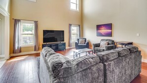 A spacious living room with a large sectional sofa, a flat-screen TV, and a painting on the wall. - 10 Mi to Gulfport Beaches: Family Home w/ Patio (Gulfport)