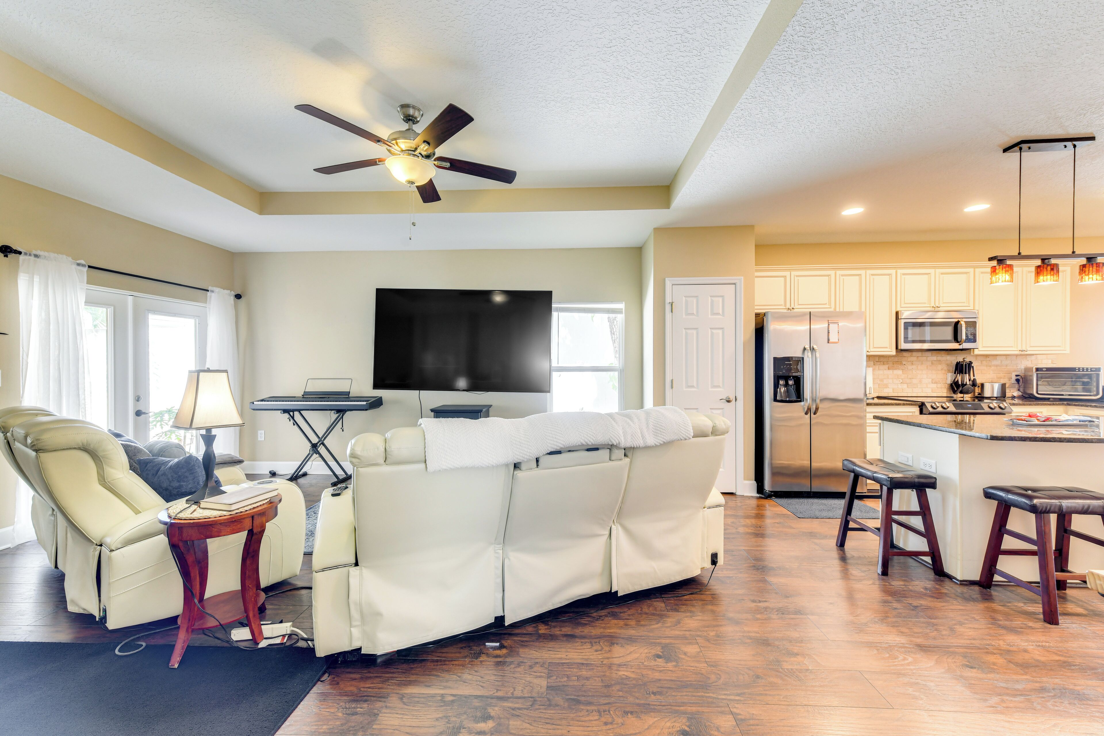 A modern living room with a sofa, a ceiling fan, and a flat-screen TV.