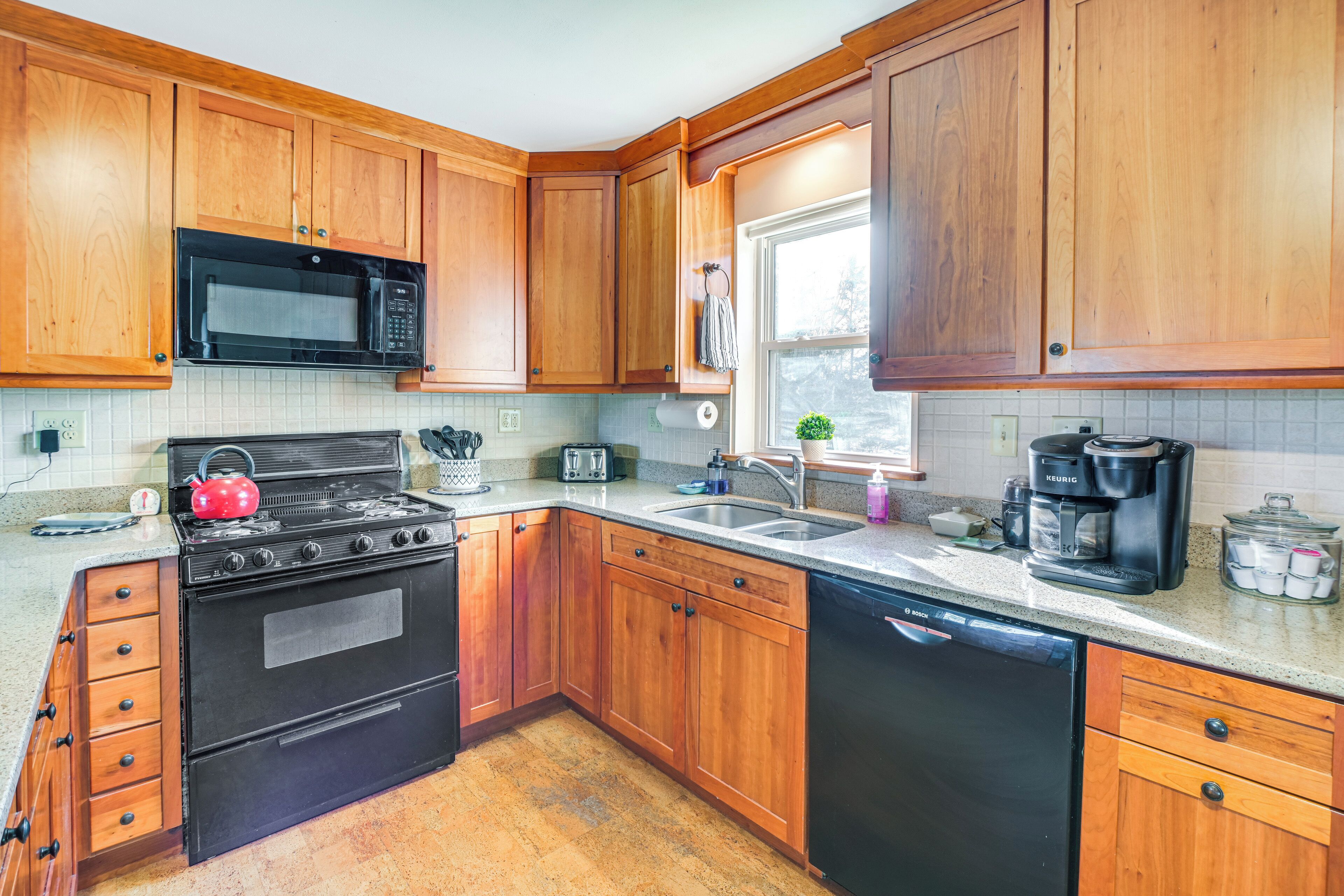 A kitchen with wooden cabinets, a stove, a microwave, a dishwasher, and a coffee maker.