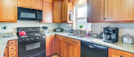 A kitchen with wooden cabinets, a stove, a microwave, a dishwasher, and a coffee maker.