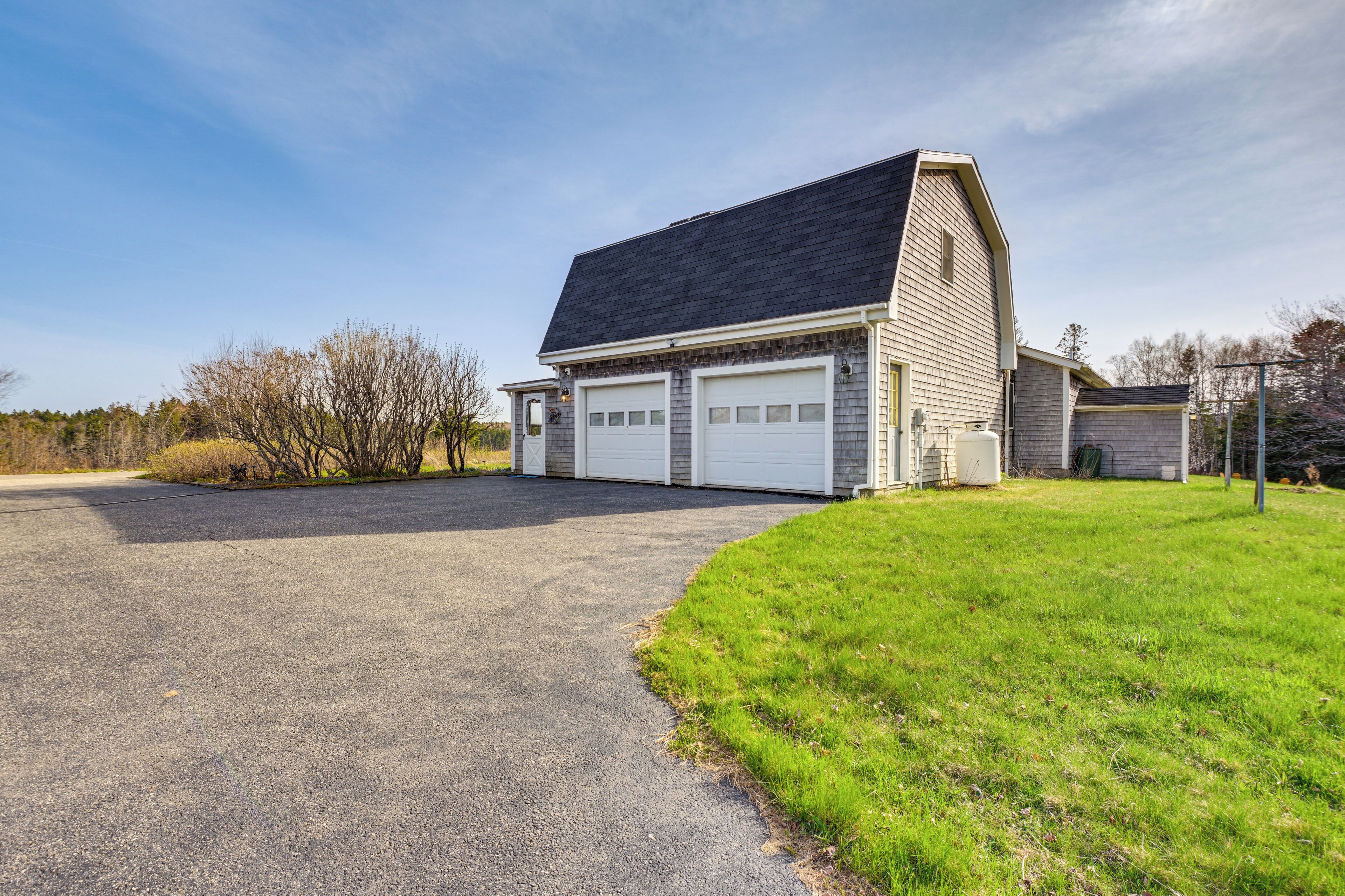 A two-story building with a garage, a sloped roof, and a paved driveway.