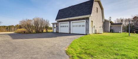 A two-story building with a garage, a sloped roof, and a paved driveway.