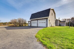 A two-story building with a garage, a sloped roof, and a paved driveway. - Bay Views: Peaceful Acadia National Park Getaway! (Steuben)