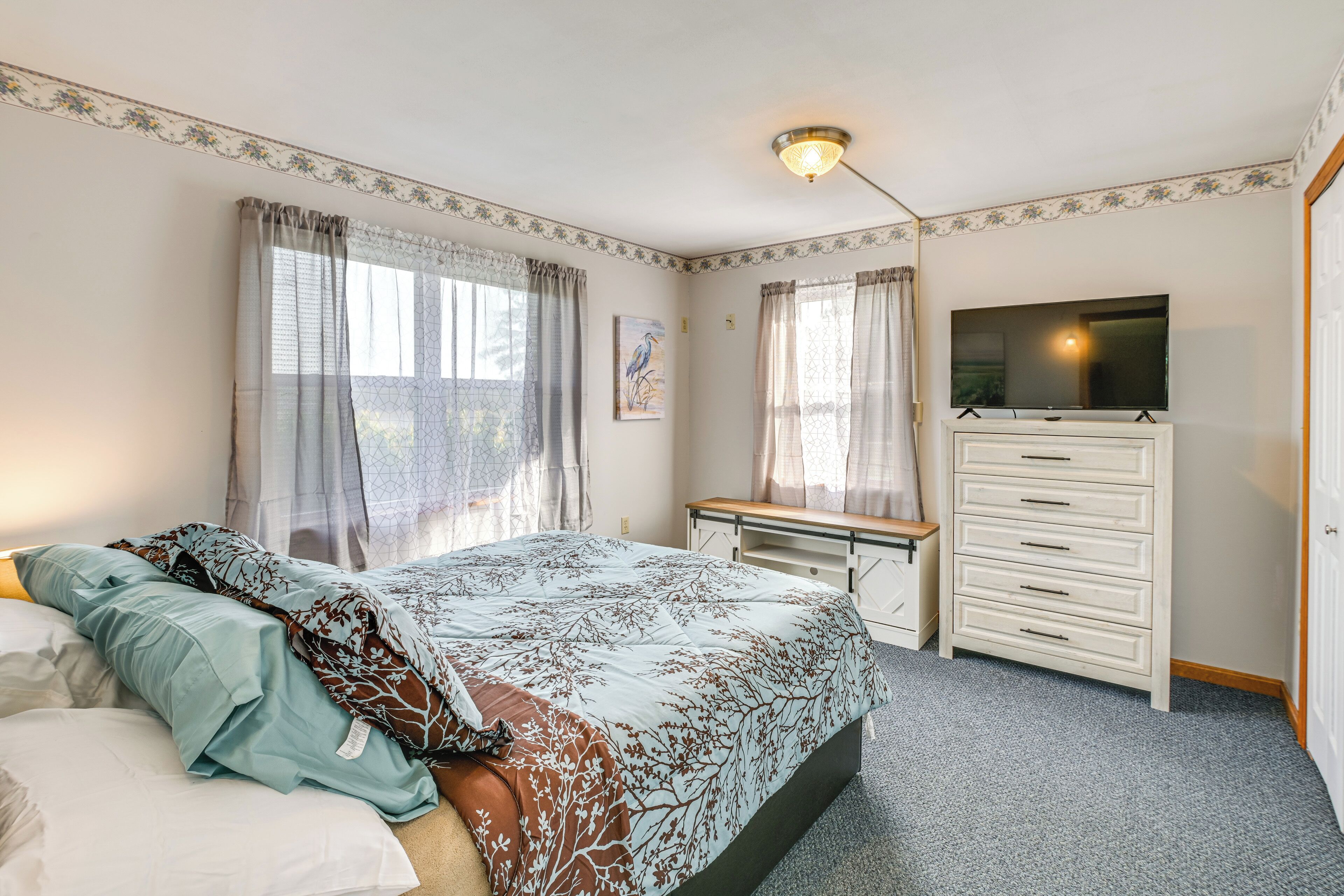 Une chambre à coucher comprenant un lit, un bureau, une commode et un téléviseur.