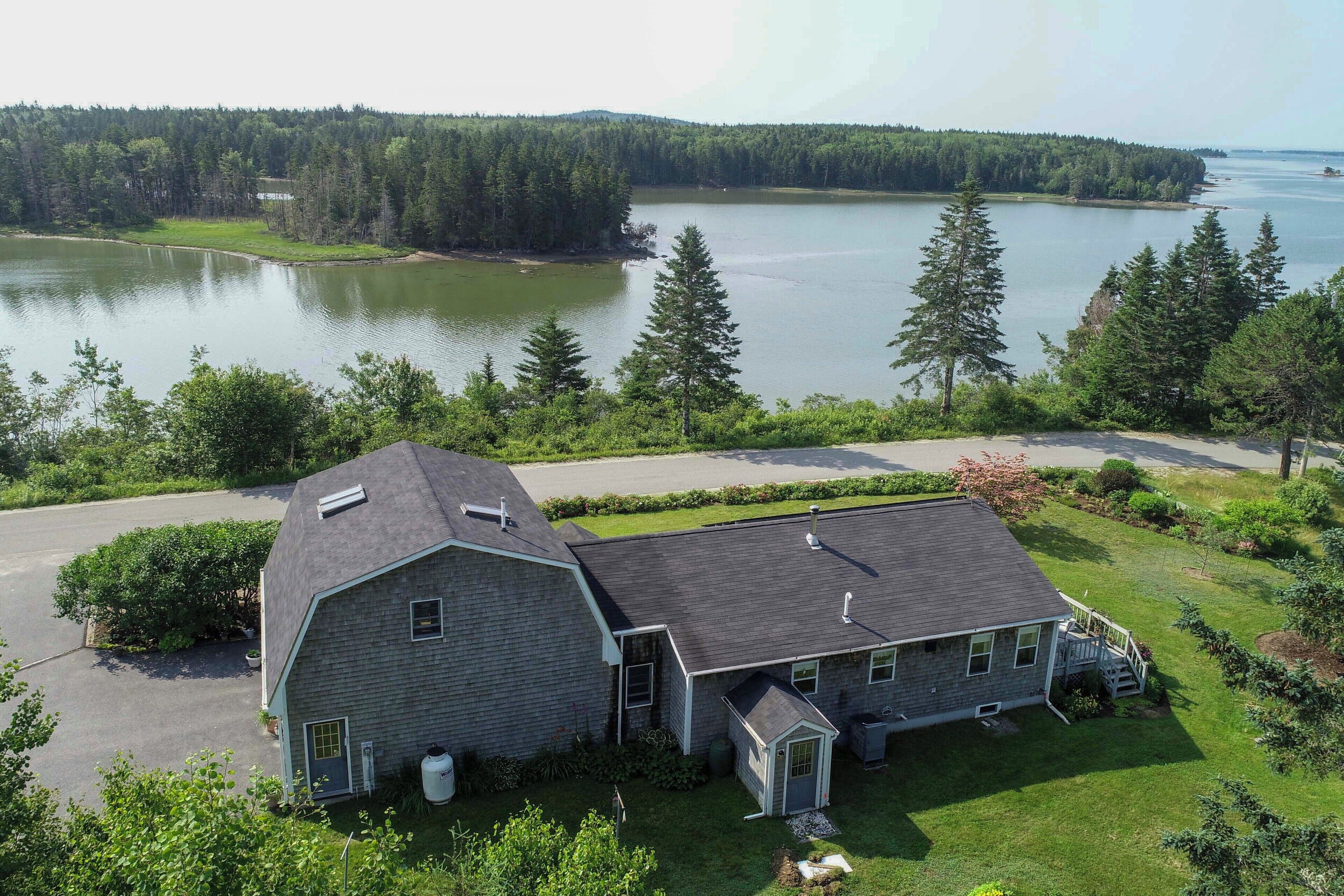 A two-story house with a large garage and a covered porch, surrounded by a well-maintained lawn and a lake view.