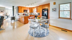 Une cuisine moderne avec des meubles en bois, un îlot central et un coin repas comprenant une table ronde et des chaises.