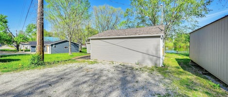 A residential area with a gravel driveway, a small shed, and a house with a gray roof.