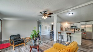 A modern living room with a sofa, a coffee table, and a black leather chair. A kitchen with a bar area is visible in the background. - Near Hiking & Fishing: Dale Home w/ Deck! (Dale)