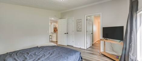 A bedroom with a bed, a TV on a wooden stand, and a door leading to a bathroom.