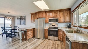 A modern kitchen with wooden cabinets, stainless steel appliances, a large island, and a view of the outdoors. - BBQ Ready: Lakefront Retreat in Watertown (Watertown)