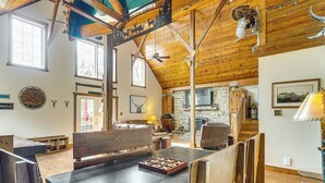 A rustic cabin interior with a wooden dining table, benches, a fireplace, and a stone wall. - 'the Lodge at Crider Creek' Getaway on 140 Acres! (Bland)