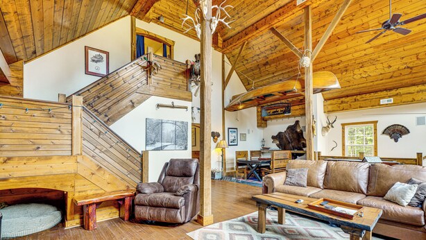 A spacious living area with a wooden staircase, leather furniture, and a ceiling fan. - 'the Lodge at Crider Creek' Getaway on 140 Acres! (Bland)