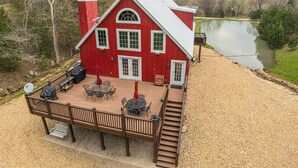 A red barn with a deck, outdoor seating, and a view of a lake. - 'the Lodge at Crider Creek' Getaway on 140 Acres! (Bland)