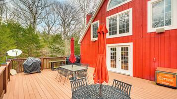 A red house with a deck, outdoor furniture, and a satellite dish.