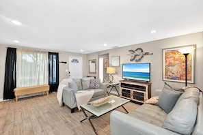 A living room with a sofa, a coffee table, a television, and a cabinet.