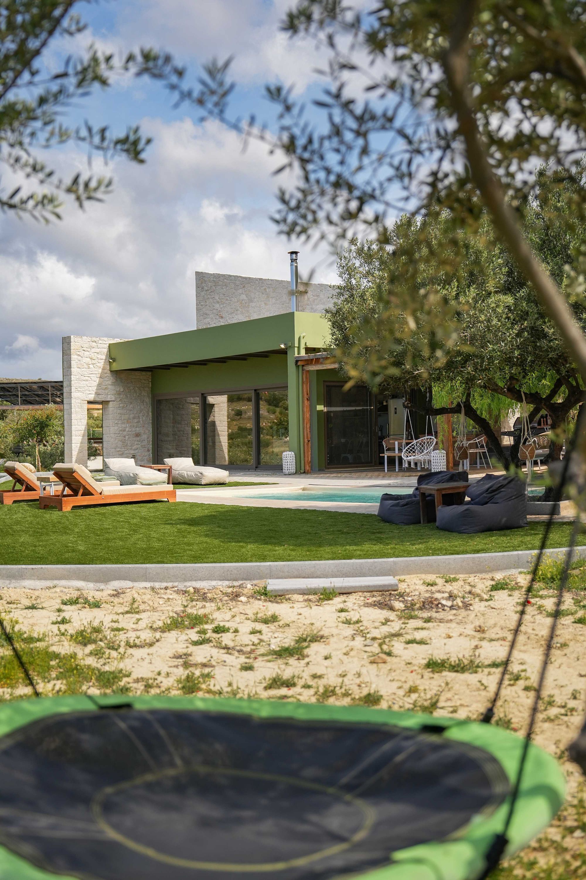 A modern building with a pool, outdoor seating, and a trampoline.