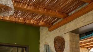 A kitchen with a stone wall, wooden cabinets, and a hanging basket. - Oliva Emerald Eco - Secluded Off-grid Vineyard Villa (Hersonissos)